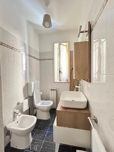 a white bathroom with a toilet and a sink at L'host in Taormina in Taormina