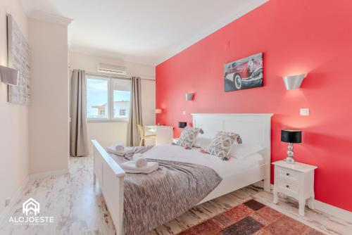 a bedroom with a red wall with a bed at Ocean Paradise - Apartment with ocean view in Ericeira