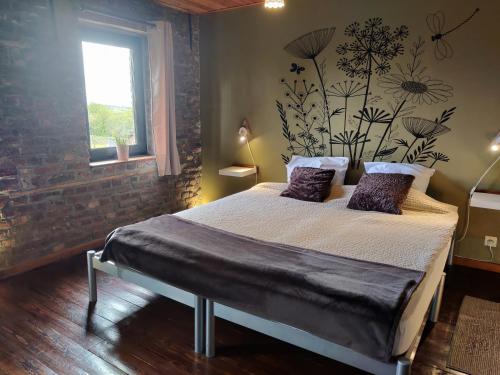 1 dormitorio con 1 cama con pared de ladrillo en La Ferme du Pré Charmant, en Grandhan