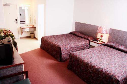 Habitación de hotel con 2 camas y mesa en Country Club Inn en Lacombe