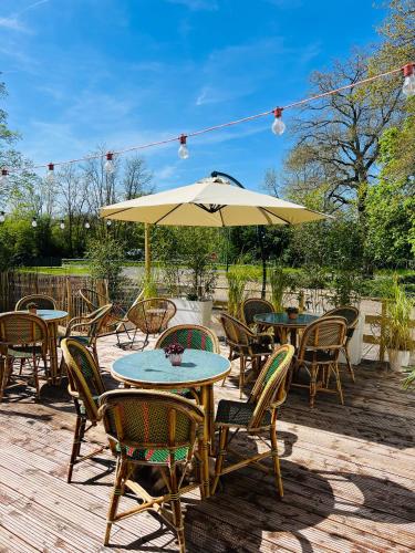 un patio avec tables, chaises et un parasol dans l'établissement Motel Les Broussailles, à Mesves-sur-Loire