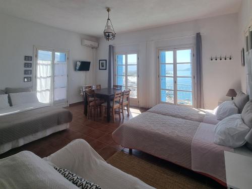 um quarto com 2 camas, uma mesa e cadeiras em Panoramic View em Poros