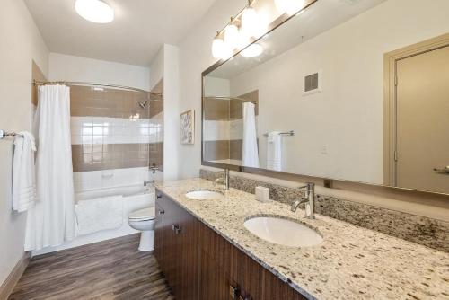 a bathroom with two sinks and a toilet and a mirror at Landing at Market Square Tower - 2 Bedrooms in Downtown Houston in Houston