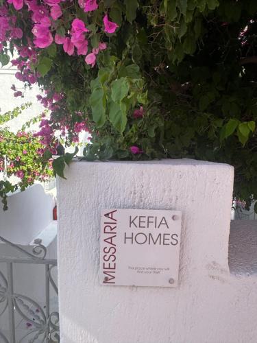 a sign on a white wall with flowers at Kefia 2 in Mesaria