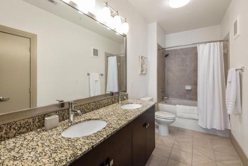 ein Badezimmer mit zwei Waschbecken, einem WC und einem Spiegel in der Unterkunft Landing at 99 Front - 2 Bedrooms in Downtown Memphis in Memphis