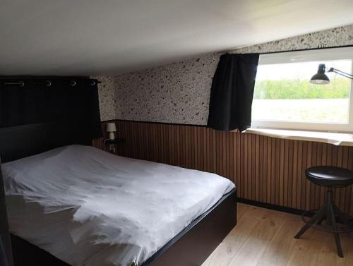ein Schlafzimmer mit einem Bett, einem Stuhl und einem Fenster in der Unterkunft La Rose du Bel Homme in Rocroi