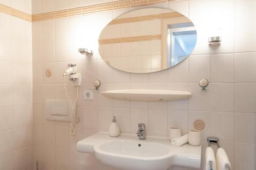 a white bathroom with a sink and a mirror at Forellenhof Wald- und Wiesenquartier in Bad Berleburg