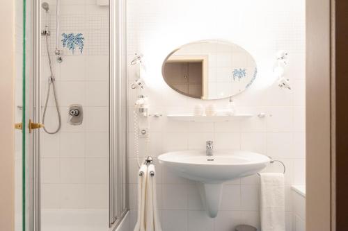a white bathroom with a sink and a mirror at Forellenhof Wald- und Wiesenquartier in Bad Berleburg