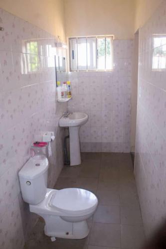 a white bathroom with a toilet and a sink at Résidence ABZ Azally in Abomey