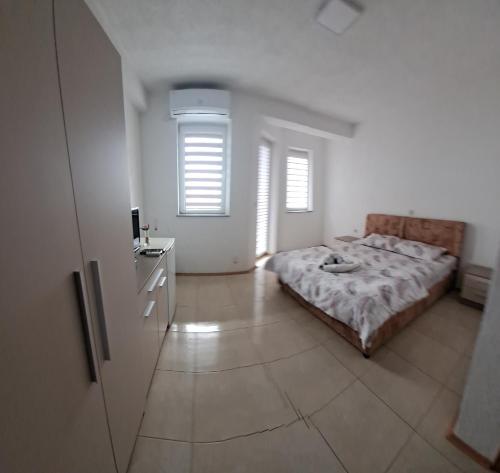 a bedroom with a bed and a dresser and two windows at Villa&Restaurant Strmec in Elshani