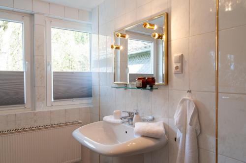 a white bathroom with a sink and a mirror at Forellenhof Wald- und Wiesenquartier in Bad Berleburg
