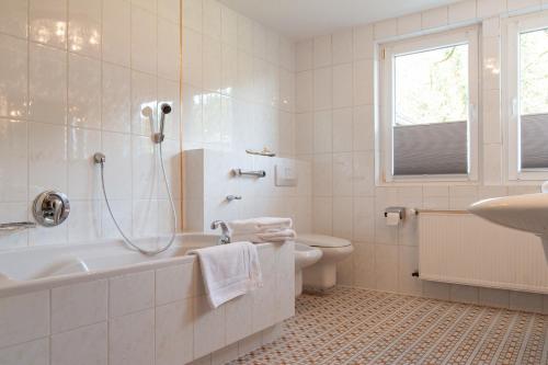 a bathroom with a tub and a toilet and a sink at Forellenhof Wald- und Wiesenquartier in Bad Berleburg
