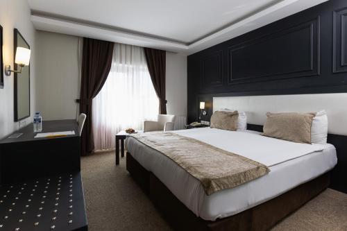 a bedroom with a bed and a desk and a window at Bonjur Hotel Thermal & Wellness Club in Ankara