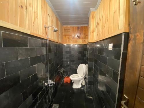 a bathroom with a toilet and black tiled walls at Resort66Villa2 in Abbottābād
