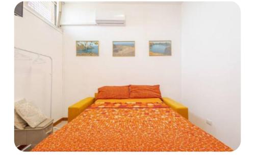 a bed with an orange bedspread in a room at Tiny house Taormina mare with sofa bed - mini stanza Taormina mare con divano letto in Taormina