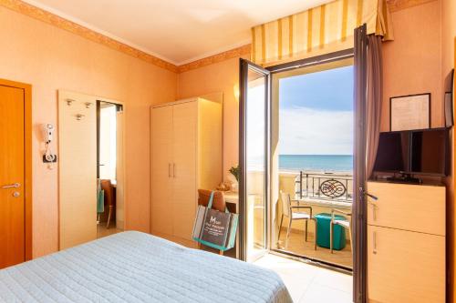 a bedroom with a bed and a view of the ocean at Hotel Metropole in Rimini