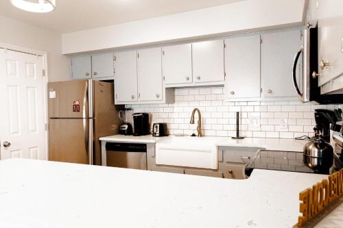 a kitchen with white cabinets and a sink and a refrigerator at Oceanfront and Modern Top Location on Ocean Blvd w Pool in Myrtle Beach