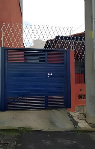 une porte de garage bleue devant une clôture dans l'établissement CasacentrocompartilhadaMogidasCruzes, à Mogi das Cruzes