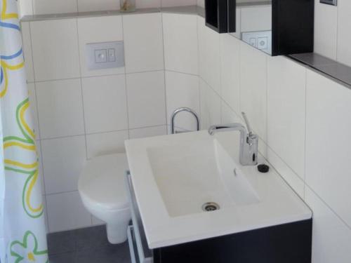 a white bathroom with a sink and a toilet at Ferienwohnung Kupfer in Niestetal