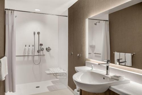 a white bathroom with a sink and a shower at SpringHill Suites by Marriott Menomonee Falls in Menomonee Falls