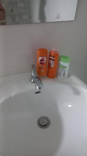 a bathroom sink with a faucet and two cups on it at CG BNB HOTEL in Chiang Mai