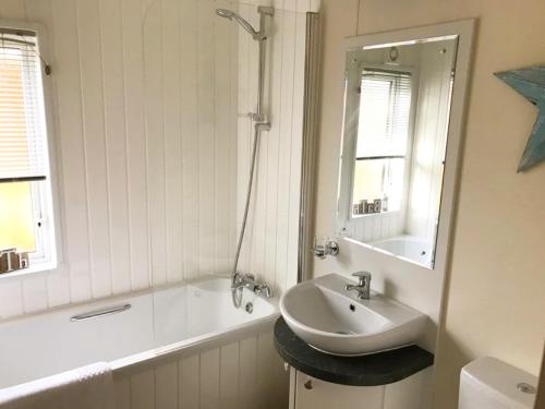 een badkamer met een wastafel, een bad en een spiegel bij Oakwood Lodge in Morpeth