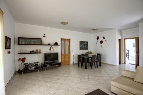 a living room with a television and a table with chairs at Seafront Home Villa in Kato Gouves