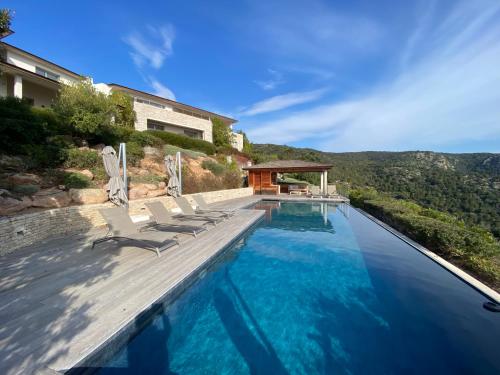 une piscine avec des chaises et une maison dans l'établissement Luxury Villa Agnese l Sea view & infinity pool, à Porto-Vecchio
