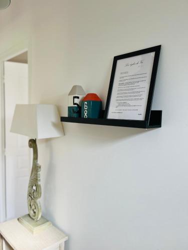 a shelf with a lamp and a picture on a wall at Le 4 Maison de charme proche de la plage wifi in Barneville-Carteret