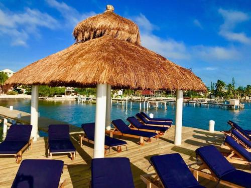 a deck with chairs and a straw umbrella and the water at VeLento Partial Ocean View #8 in Caye Caulker