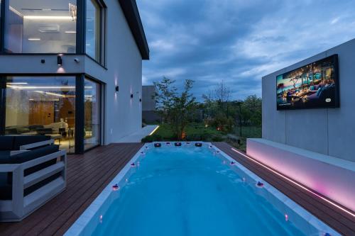 a house with a swimming pool and a tv on the wall at Chandelier Sky Mansion in Prague
