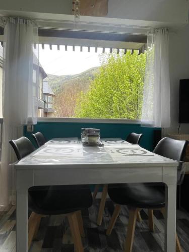 une table de salle à manger avec des chaises et une grande fenêtre dans l'établissement Appartement confortable labellisé saint lary, à Vignec