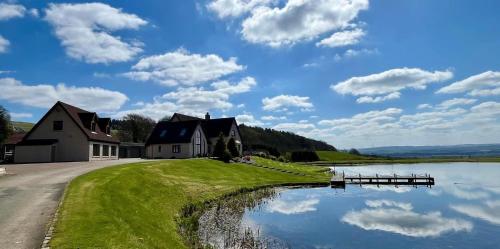 a house on the side of a lake with a bridge at The Hoose at The Vu in Bathgate