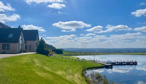 a house on the side of a lake with a dock at The Hoose at The Vu in Bathgate