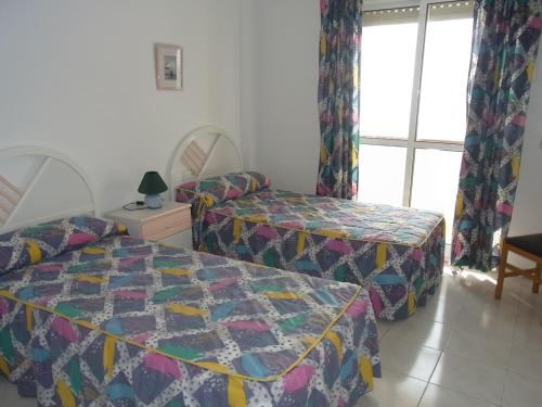 1 dormitorio con 2 camas y ventana en Residencial Los Ibicencos V.v., en La Manga del Mar Menor