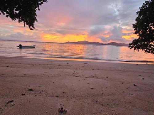 um barco na água em uma praia ao pôr do sol em La Digue Luxury Beach & Spa em La Digue