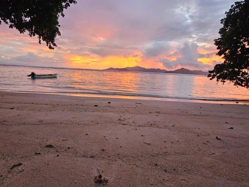 a boat in the water on a beach at sunset at La Digue Luxury Beach & Spa in La Digue