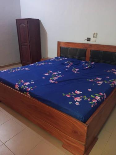 a bed with a blue comforter with flowers on it at RÉSIDENCE ABZ ABOMEY in Abomey