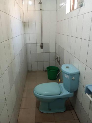 a bathroom with a blue toilet and a green bucket at RÉSIDENCE ABZ ABOMEY in Abomey