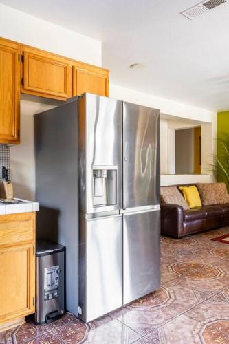 a stainless steel refrigerator in a kitchen with a couch at Desert Sun Flower: Private Spa, pool, Golf area in Coachella