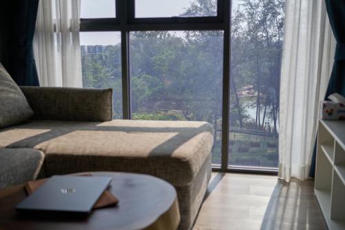 ein Wohnzimmer mit einem Sofa und einem großen Fenster in der Unterkunft Modern 2-bedroom Apartments Garden view in Skypark Laguna Bang Tao in Strand Bang Tao