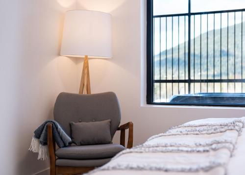 a bedroom with a chair and a lamp and a window at Drop in Condo by Revelstoke Vacations in Revelstoke