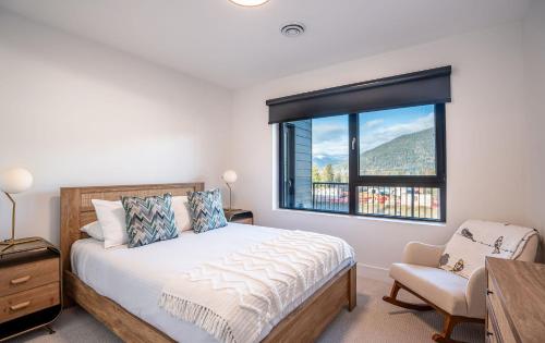 1 dormitorio con cama, ventana y silla en Drop in Condo by Revelstoke Vacations en Revelstoke