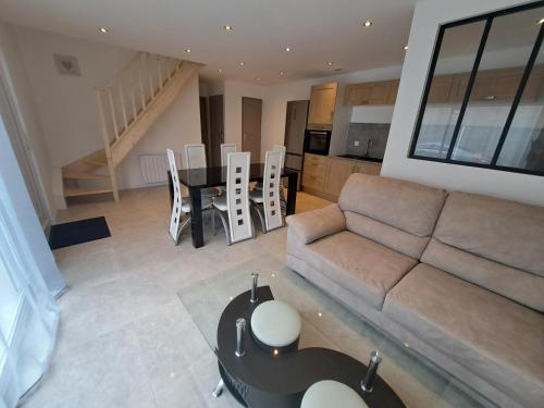 un salon avec un canapé et une table dans l'établissement Gites des falaises de Longues 6personnes, à Longues-sur-Mer