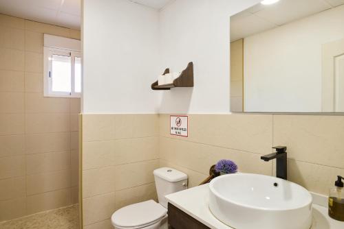 ein Badezimmer mit Waschbecken, Toilette und Spiegel in der Unterkunft Casa Rural Olivar de la Marquesa in La Carlota
