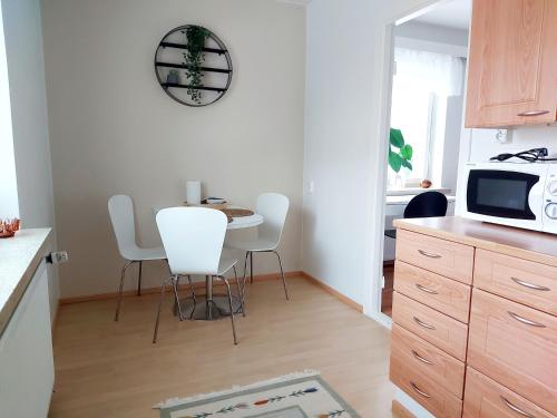 een keuken met een tafel en stoelen en een magnetron bij Spacious studio apartment near the center of Joensuu in Joensuu