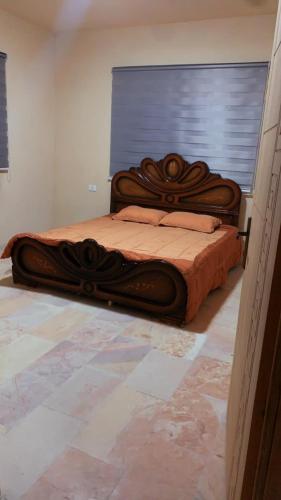 un letto in legno in una camera con finestra di الاردن ad Al-Salṭ