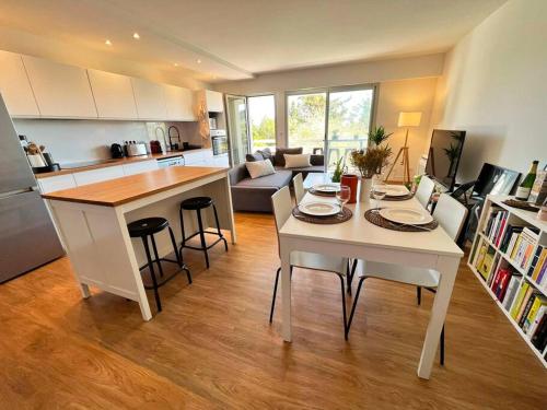 une cuisine et un salon avec une table et des chaises blanches dans l'établissement Superbe Appartement, Cap d'Antibes - Clim, Parking, Terrasse vue mer, à Antibes