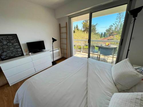 une chambre avec un grand lit blanc et un balcon dans l'établissement Superbe Appartement, Cap d'Antibes - Clim, Parking, Terrasse vue mer, à Antibes