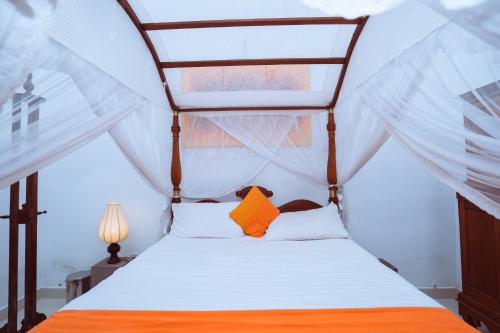 a bedroom with a canopy bed with orange and white pillows at The Koarale Bungalow in Matara